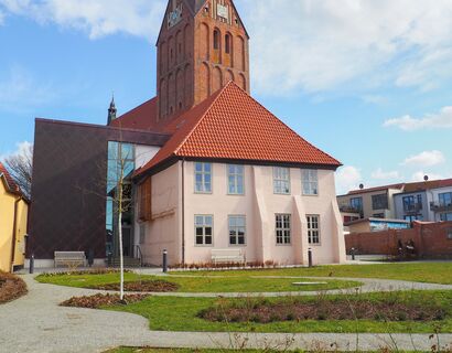 Ältester Profanbau Mecklenburg-Vorpommerns. Großes Haus mit Garten und Kirche im Hintergrund