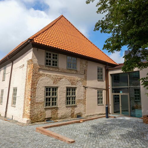 Haus von der Vorderseite mit Eingang rechts, hinten links der Garten